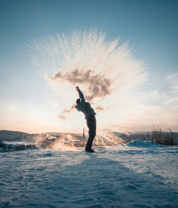 Silhouette of a person in a dynamic stretching pose against a bright sunrise.